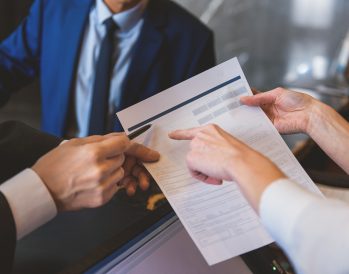 a succesful hotel sales manager holding a contract and pointing to where the client should sign.