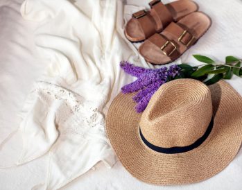 beach sandals, hat, and lavender sitting on a bed