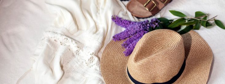 beach sandals, hat, and lavender sitting on a bed
