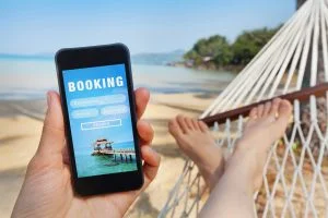 Person with phone in hammock booking a vacation