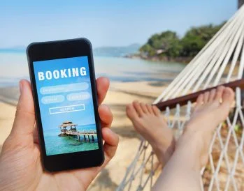 Person with phone in hammock booking a vacation