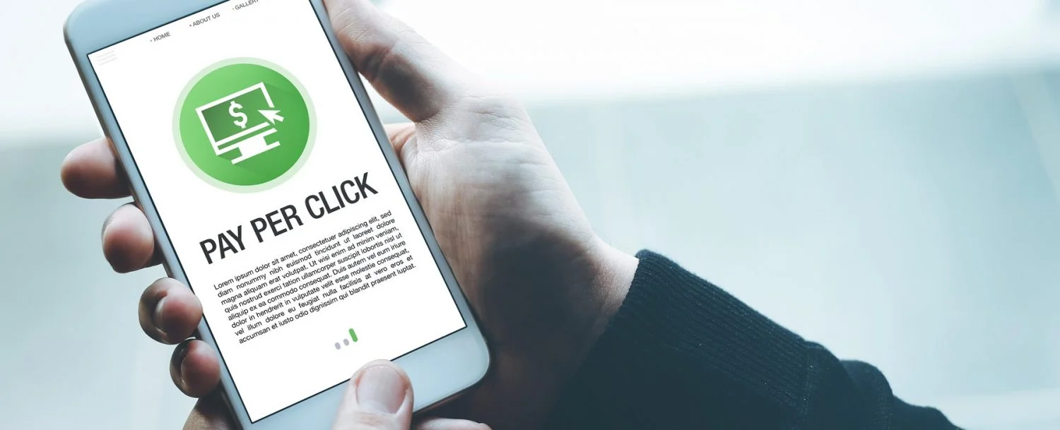 Person holding a mobile phone with an image that reads pay per click