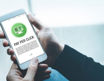Person holding a mobile phone with an image that reads pay per click