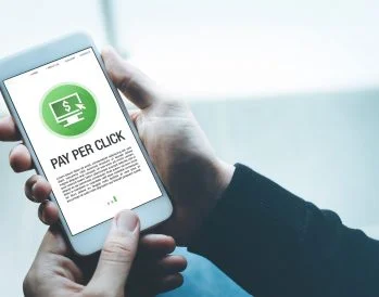Person holding a mobile phone with an image that reads pay per click