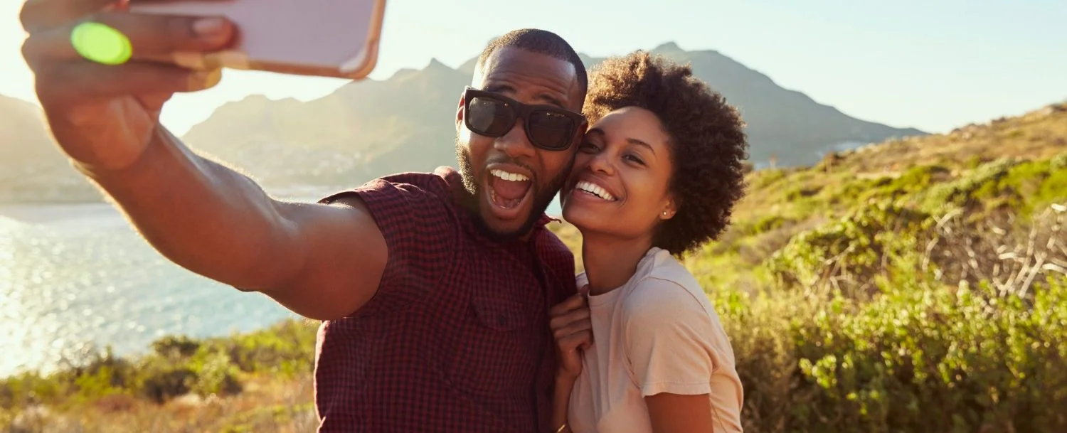 Couple taking a selfie with mountains behind them