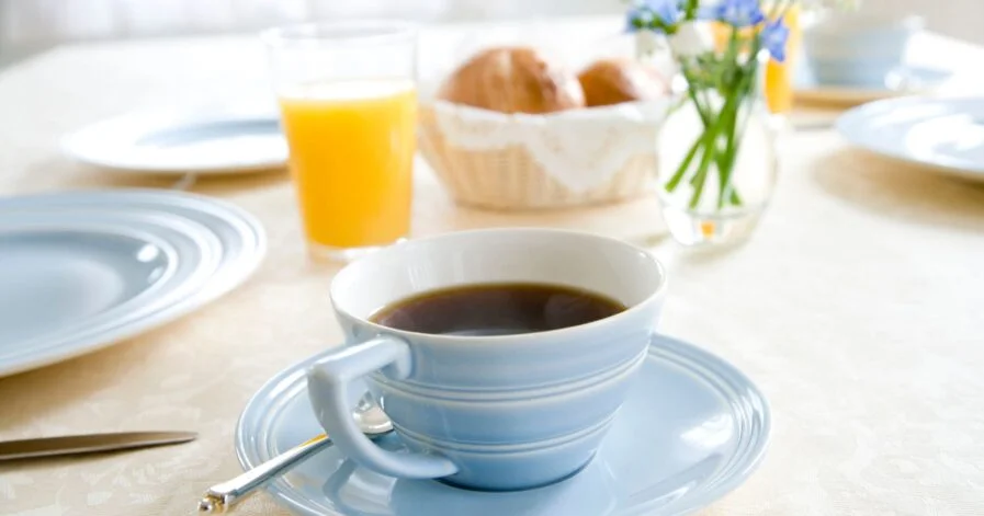 coffee being served on a plate with breakfast food in the background
